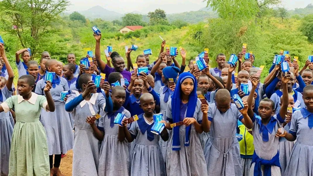 Girls celebrating together, holding dignity packages aloft